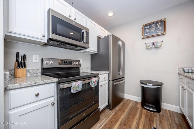 kitchen with light stone countertops, white cabinetry, and stainless steel appliances