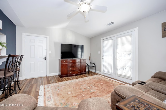 living room with ceiling fan, vaulted ceiling, and light wood-type flooring