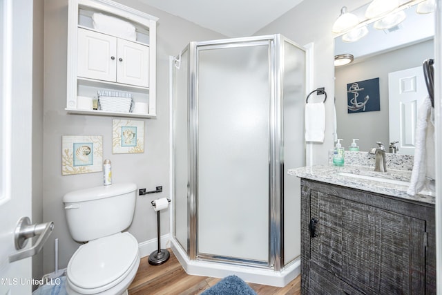 bathroom featuring hardwood / wood-style floors, vanity, toilet, and a shower with door