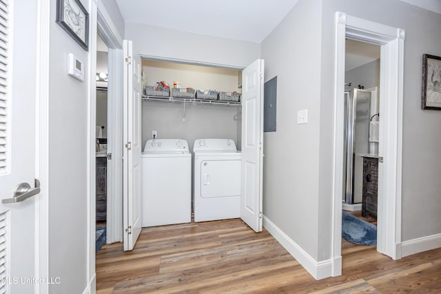 clothes washing area featuring hardwood / wood-style flooring, washer and dryer, and electric panel