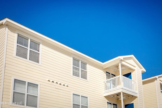 view of side of home with ceiling fan and a balcony