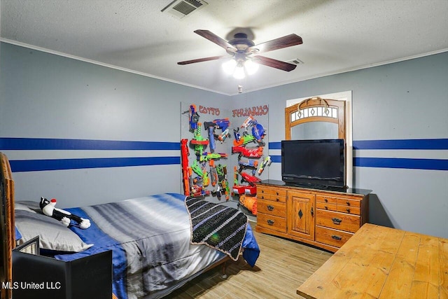 bedroom with ceiling fan, ornamental molding, light hardwood / wood-style floors, and a textured ceiling