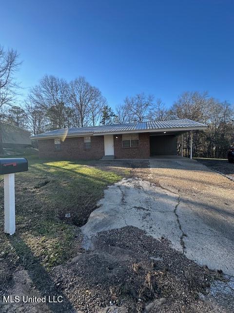 view of front of house featuring driveway, a carport, and brick siding