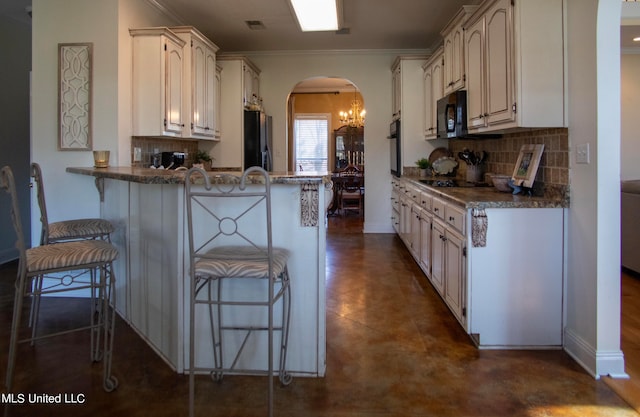 kitchen with tasteful backsplash, a breakfast bar, crown molding, black appliances, and white cabinetry