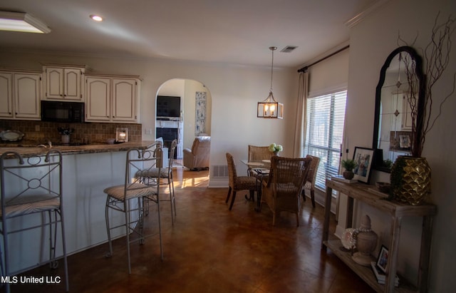 kitchen with an inviting chandelier, tasteful backsplash, pendant lighting, a breakfast bar area, and ornamental molding