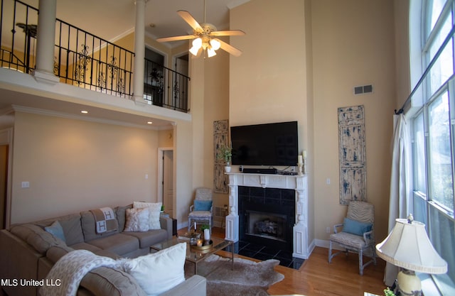 living room featuring ceiling fan, dark hardwood / wood-style flooring, a towering ceiling, and a fireplace