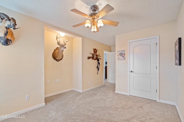 carpeted spare room featuring a textured ceiling and ceiling fan