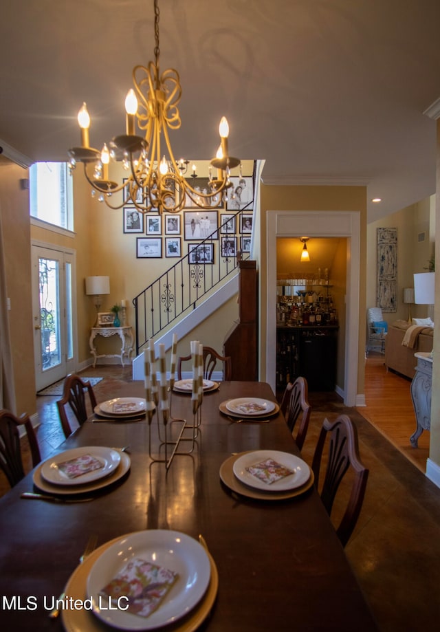 dining room with wood-type flooring, ornamental molding, and a notable chandelier