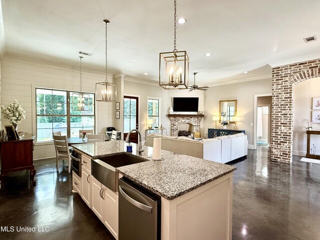 kitchen with a sink, stainless steel dishwasher, a chandelier, finished concrete flooring, and a fireplace