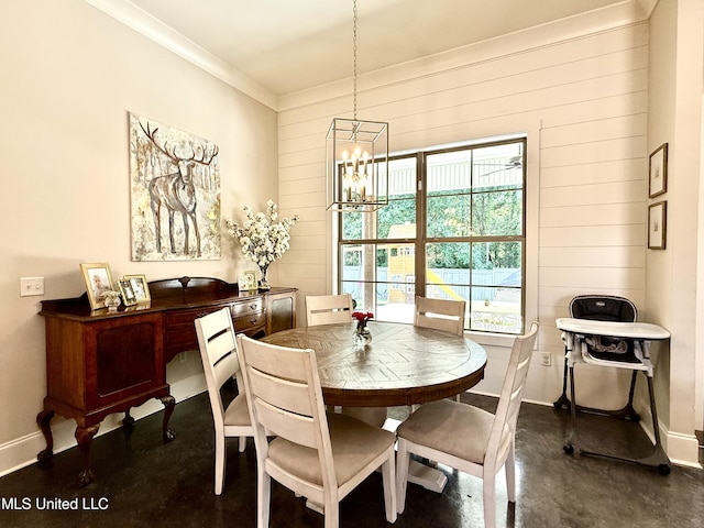 dining area with a chandelier, baseboards, wood walls, crown molding, and finished concrete flooring