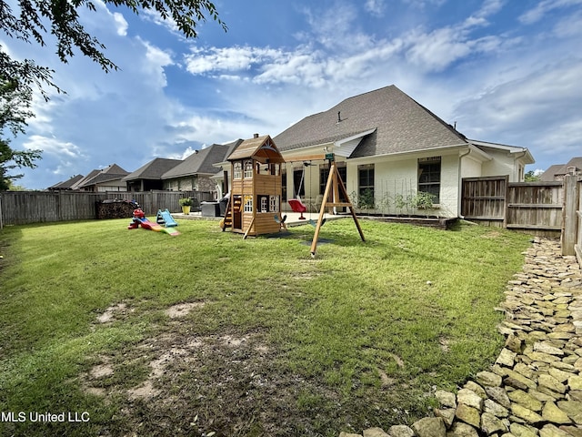 back of house featuring a playground, roof with shingles, and stucco siding