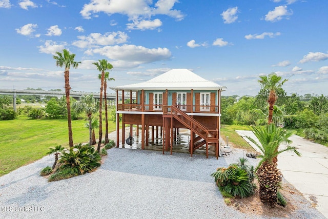 218 Front St, Pass Christian, MS 39571 - raised beach house featuring stairs, a front lawn, gravel driveway, and a porch