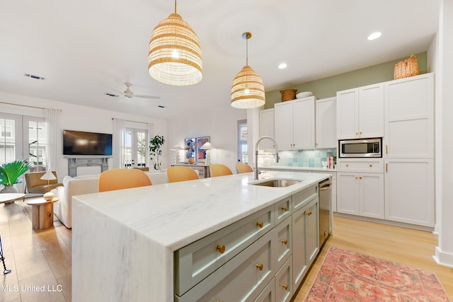 218 Front St, Pass Christian, MS 39571 - kitchen with a sink, stainless steel appliances, tasteful backsplash, pendant lighting, and light wood-style floors