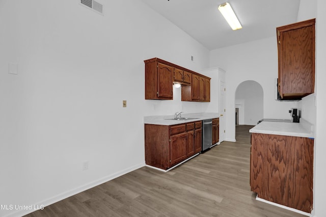 kitchen with visible vents, arched walkways, light wood-style flooring, stainless steel dishwasher, and a sink