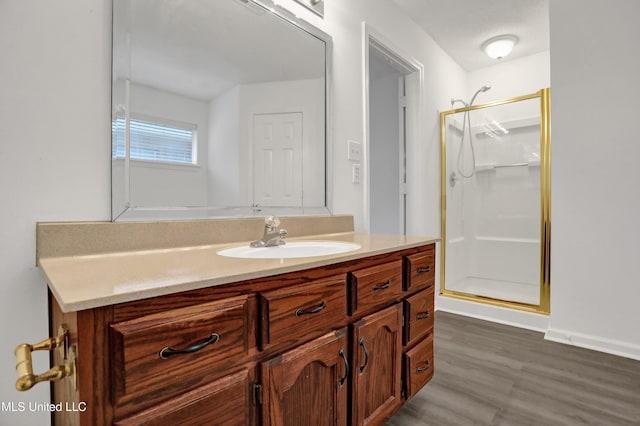 full bathroom with a shower stall, wood finished floors, and vanity