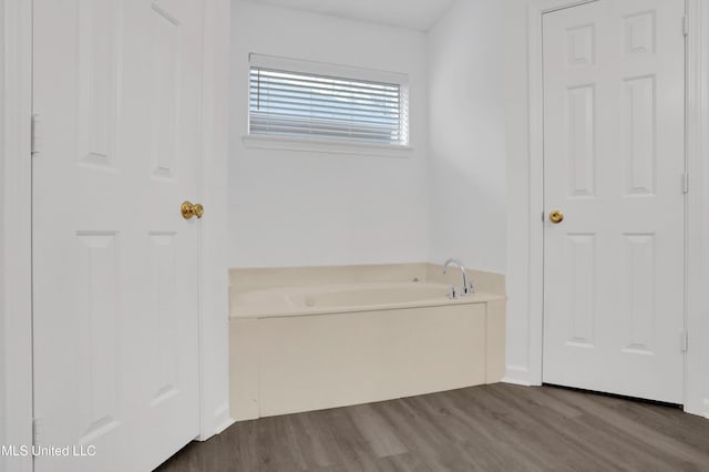 bathroom with a bath and wood finished floors