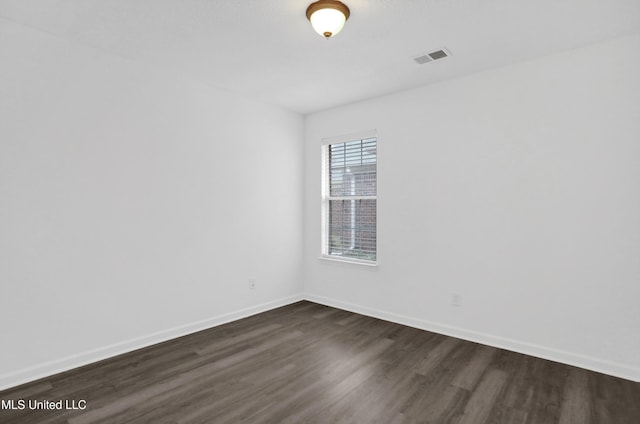 empty room with visible vents, baseboards, and dark wood-type flooring