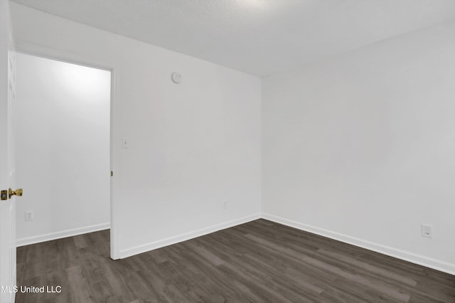 empty room featuring dark wood-type flooring and baseboards