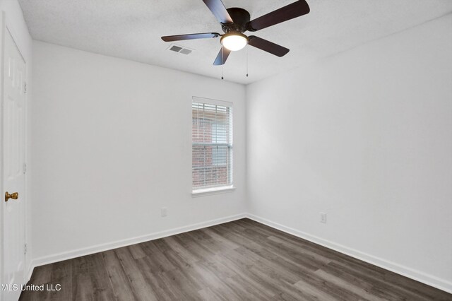 empty room with visible vents, dark wood finished floors, baseboards, and ceiling fan