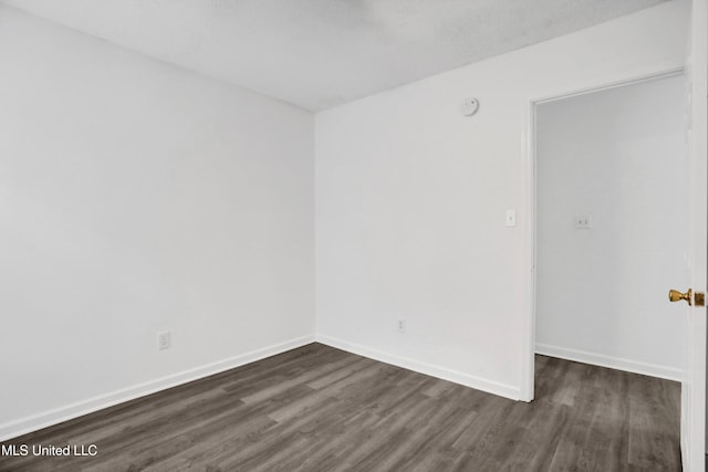 unfurnished room with baseboards and dark wood finished floors