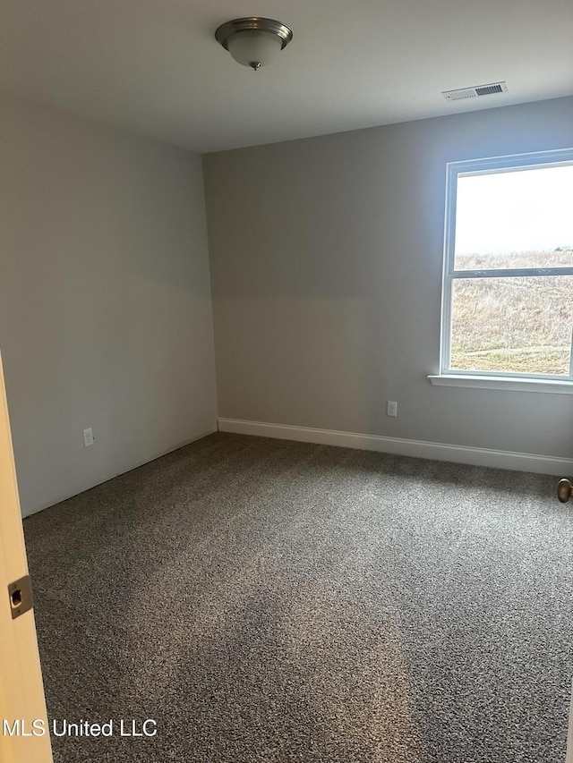 empty room with carpet floors, visible vents, and baseboards