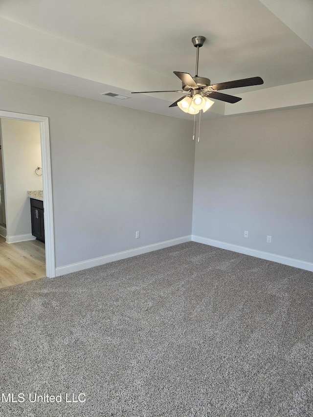 empty room with baseboards, visible vents, ceiling fan, and light colored carpet