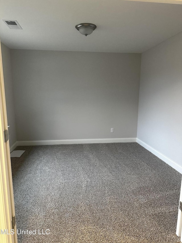 empty room with carpet, visible vents, and baseboards