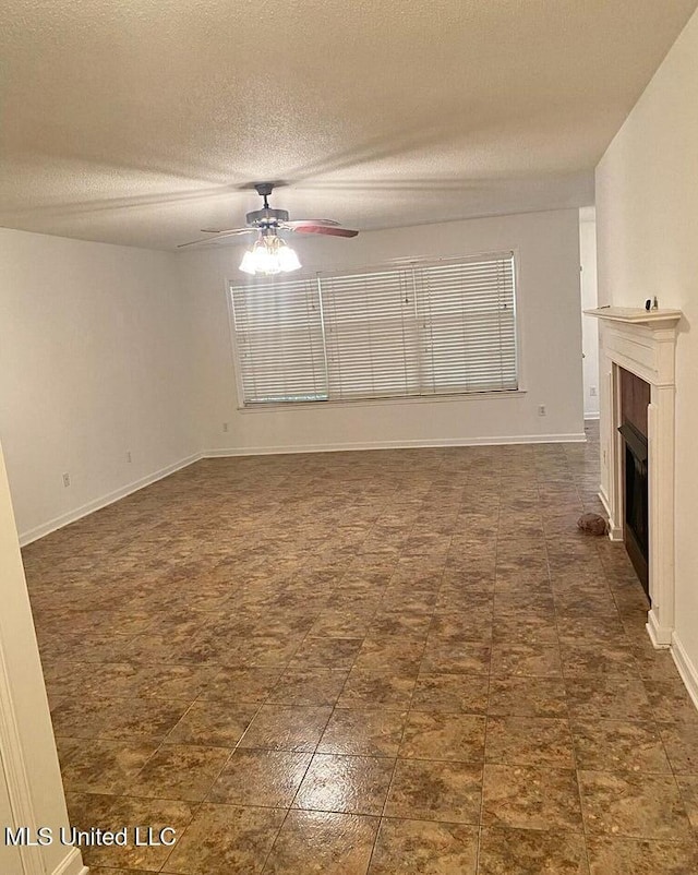 unfurnished living room featuring ceiling fan and a textured ceiling