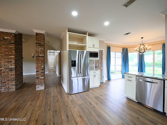 6936 Aulena Pl, Diamondhead, MS 39525 - kitchen with appliances with stainless steel finishes, ornate columns, wood finished floors, white cabinetry, and crown molding