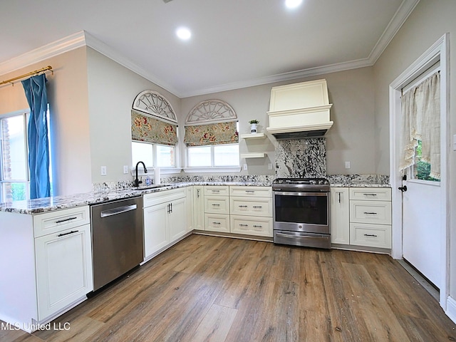 6936 Aulena Pl, Diamondhead, MS 39525 - kitchen featuring stainless steel appliances, dark wood finished floors, ornamental molding, light stone counters, and custom exhaust hood