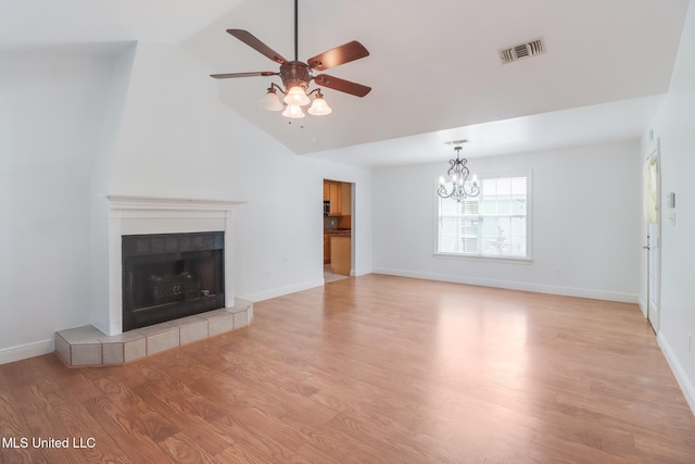 1025 Shipp St, Waveland, MS 39576 - unfurnished living room featuring ceiling fan, light wood finished floors, a chandelier, a tiled fireplace, and vaulted ceiling