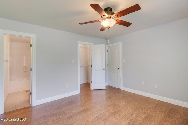 1025 Shipp St, Waveland, MS 39576 - unfurnished bedroom featuring light wood-style floors, a walk in closet, baseboards, connected bathroom, and a closet