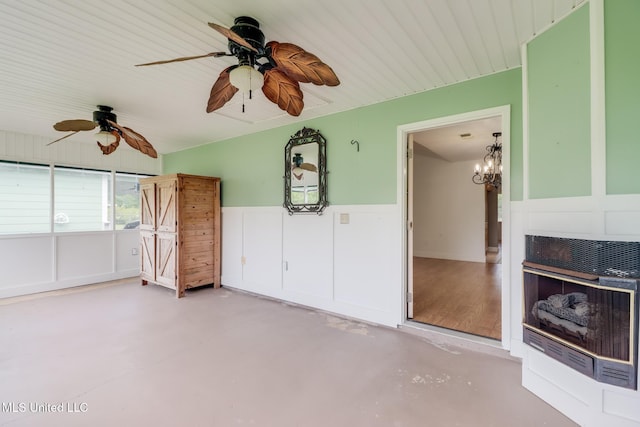 1025 Shipp St, Waveland, MS 39576 - unfurnished living room featuring ceiling fan, a wainscoted wall, finished concrete floors, a decorative wall, and a chandelier