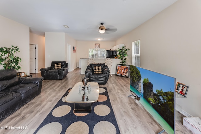 living room with light hardwood / wood-style flooring and ceiling fan