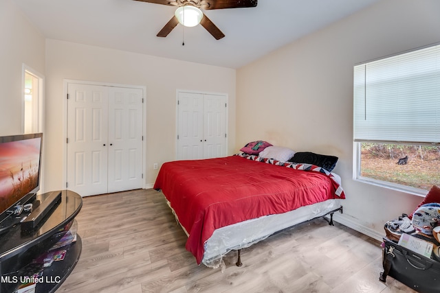 bedroom featuring multiple closets, hardwood / wood-style flooring, and ceiling fan