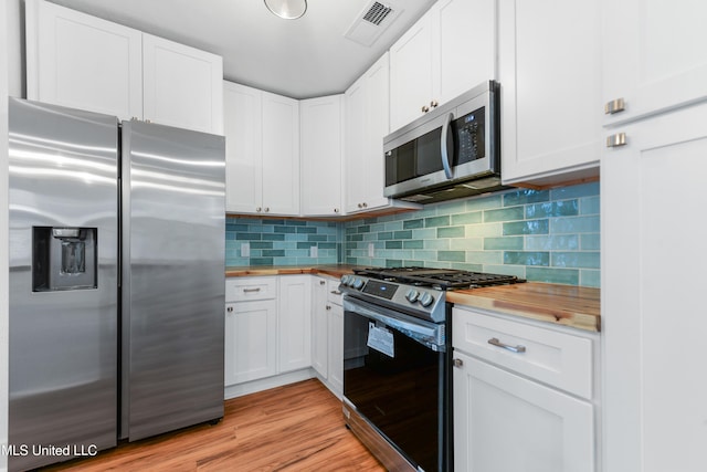2312 6th Ave, Gulfport, MS 39501 - kitchen featuring appliances with stainless steel finishes, butcher block countertops, white cabinetry, tasteful backsplash, and light wood-style floors