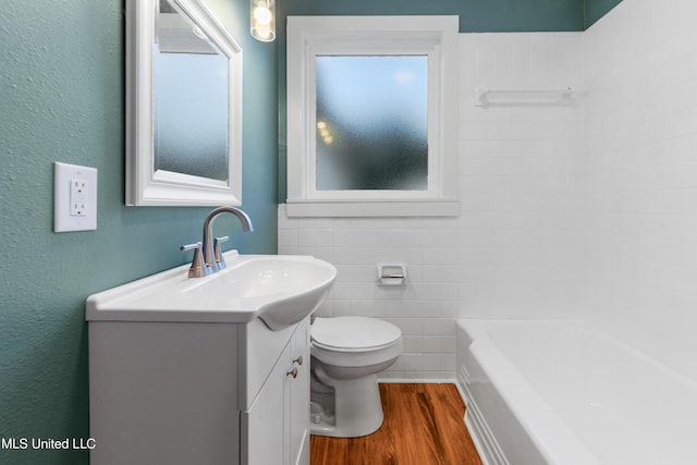 2312 6th Ave, Gulfport, MS 39501 - bathroom featuring vanity, wood finished floors, a tub to relax in, toilet, and tile walls