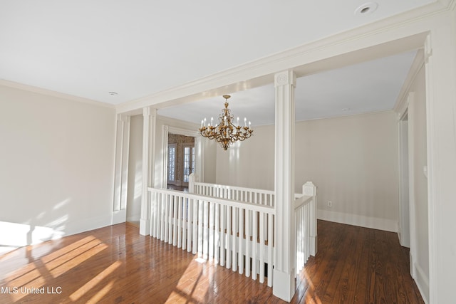 unfurnished room with baseboards, ornamental molding, wood finished floors, and an inviting chandelier