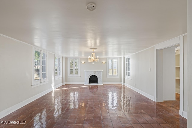 unfurnished living room with a fireplace, an inviting chandelier, and baseboards