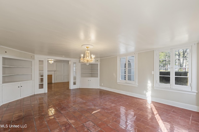 unfurnished living room featuring a chandelier, baseboards, and built in features