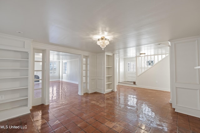 interior space with baseboards, built in features, and a notable chandelier