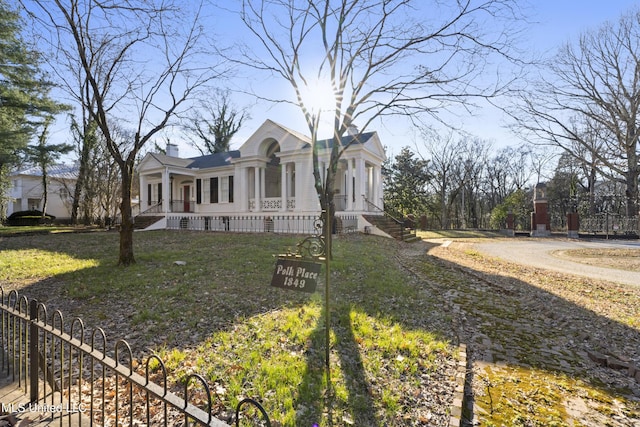 greek revival inspired property featuring a porch, a chimney, and a front lawn