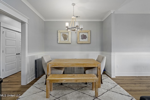 dining area featuring an inviting chandelier, ornamental molding, and dark wood-type flooring