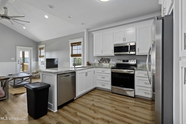 kitchen featuring lofted ceiling, white cabinets, kitchen peninsula, hardwood / wood-style flooring, and stainless steel appliances