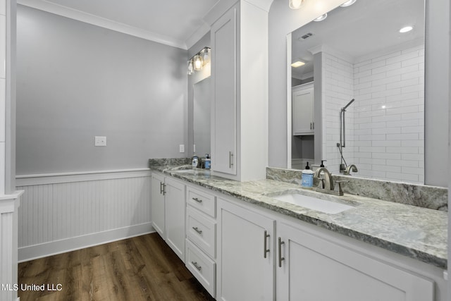 bathroom with vanity, ornamental molding, a tile shower, and wood-type flooring