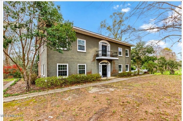 view of front of home with a balcony and brick siding