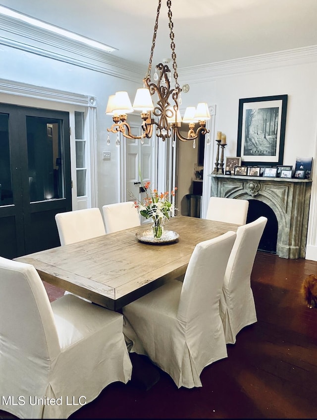 dining room with a notable chandelier, crown molding, and wood finished floors