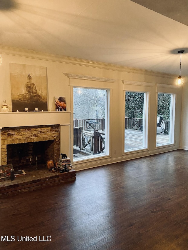 unfurnished living room featuring a fireplace with raised hearth, crown molding, and wood finished floors