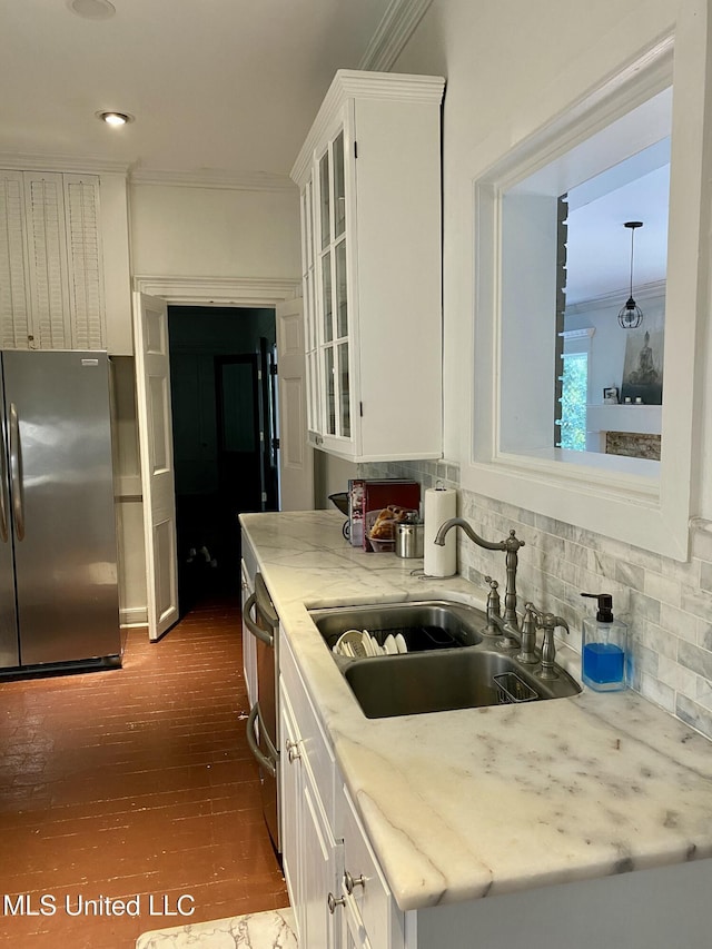 kitchen featuring appliances with stainless steel finishes, white cabinets, a sink, and ornamental molding