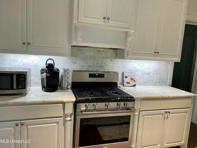 kitchen featuring under cabinet range hood, white cabinetry, appliances with stainless steel finishes, and decorative backsplash